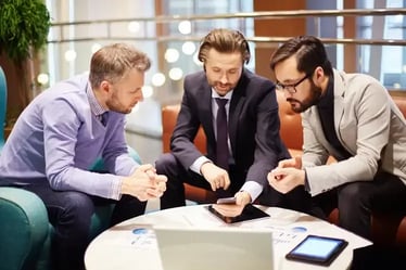 Tres colaboradores sentados en una sala observando un celular con Cisco Webex.&nbsp;